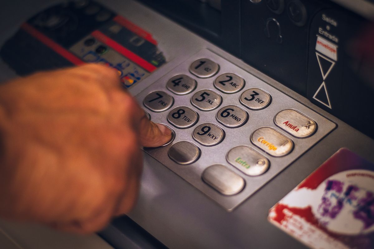 pessoa usando teclado de terminal de autoatendimento bancário
